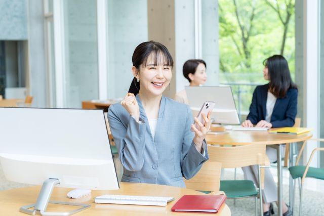 スマホをもって喜ぶ女性